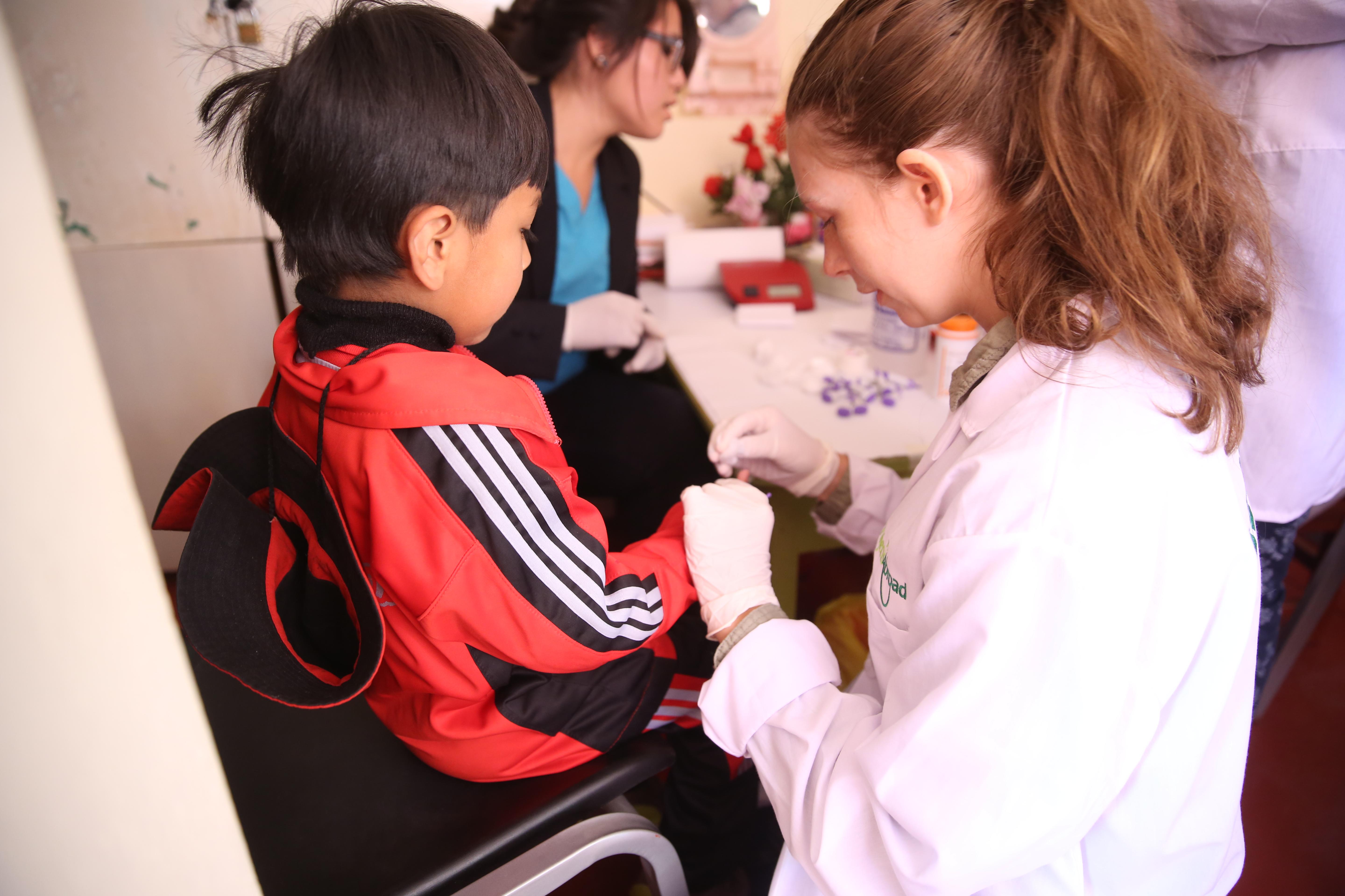 Projects Abroad female intern draws blood from a childs finger to test as part of her nursing internship in Peru. A female intern from Projects Abroad is seen drawing blood from a childs finger as part of her nursing internship in Peru.